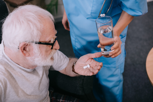 Enfermera dando un vaso de agua al paciente con pastillas
 - Foto, Imagen