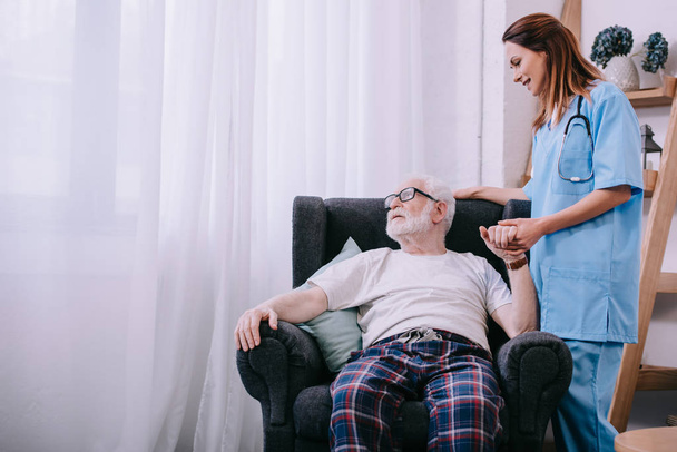 Pielęgniarka, wspieranie i trzymając rękę pacjenta starszy człowiek - Zdjęcie, obraz