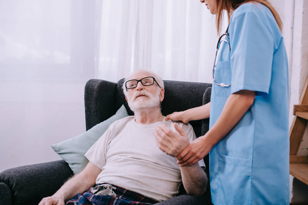 Nurse checking heartbeat of senior man - Фото, изображение