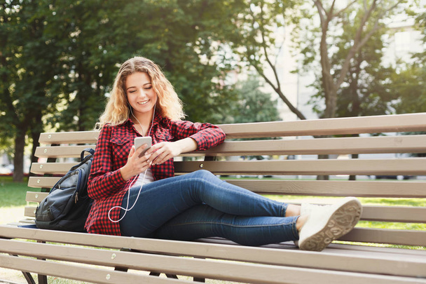 Mulher bonita sentada e ouvindo música no smartphone ao ar livre
 - Foto, Imagem