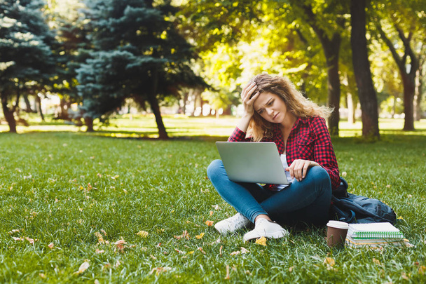 Desparate young woman using a laptop outdoors - Photo, Image
