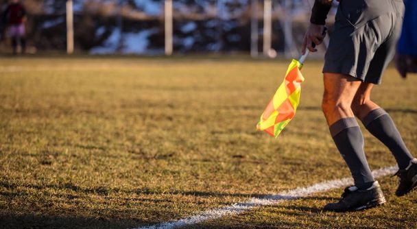 Soccer referee assistant moves at sideline with flag at hands. Blur green field,nature backdrop, close up view, banner, space. - Photo, Image