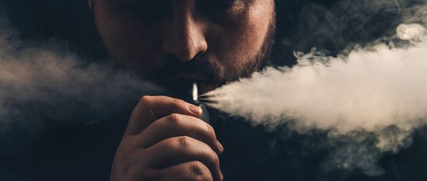 Człowieku vaping e papierosa z e ciecz, wydech dużych chmur pary z kapiącą Rda atomizer - Zdjęcie, obraz