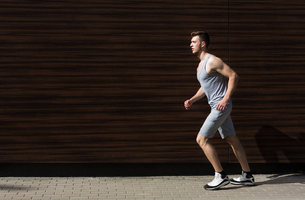Young man running in city copy space - Valokuva, kuva