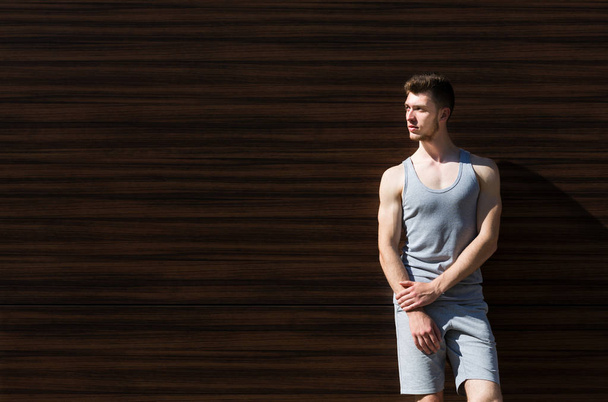 Sporty man leaning on wooden wall, copy space - Fotografie, Obrázek