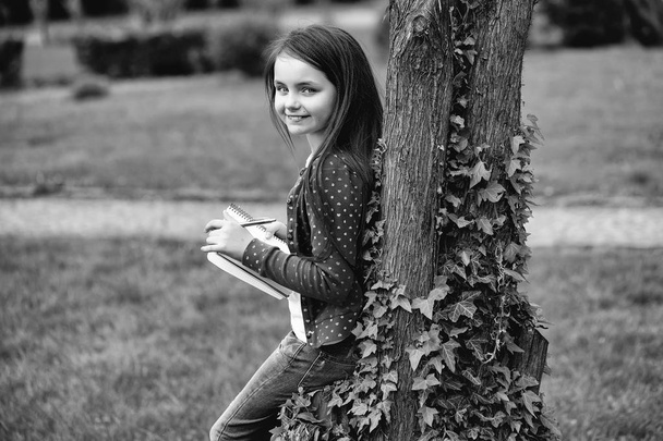 Girl with notebook and pen near tree - Zdjęcie, obraz