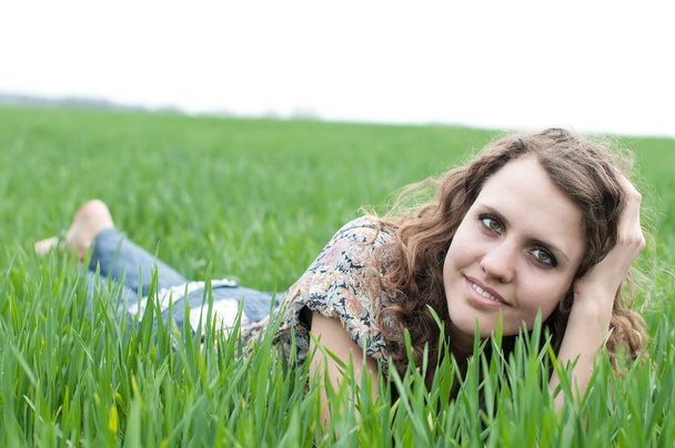 rövid haj, a zöld fű, fekvő romantikus, fiatal nő portréja álmok - Fotó, kép