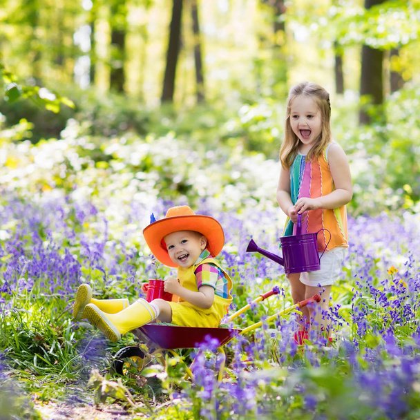 Crianças com flores de sino azul, ferramentas de jardim
 - Foto, Imagem