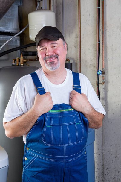 Trustworthy workman in a basement utility room - Фото, изображение