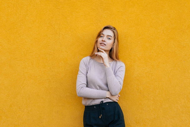 cute smiling blonde girl posing against a yellow wall background, model - Fotó, kép