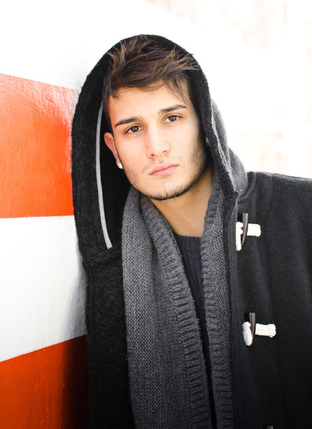 Handsome young man in hoodie against white and orange striped wall - Fotoğraf, Görsel