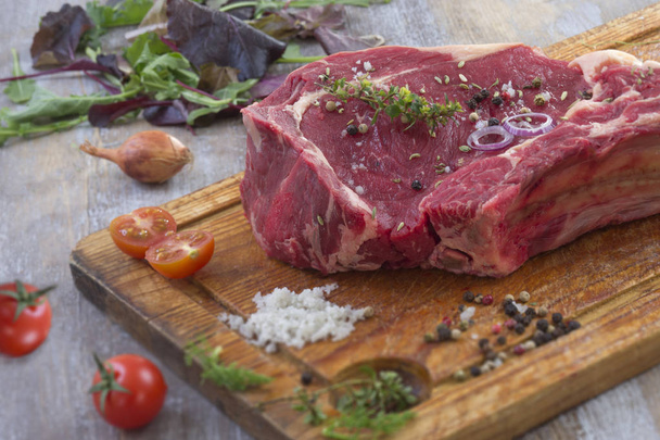Raw T-bone Steak for grill or BBQ on cutting board over on a aged wooden background, top view - Foto, imagen