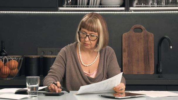 Senior kobietę w okularach uważa koszty - Zdjęcie, obraz