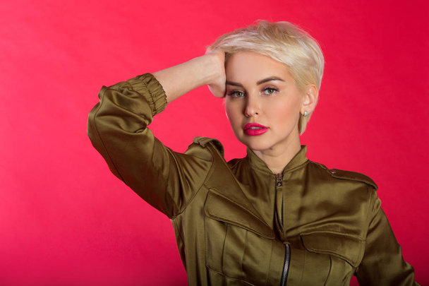 beautiful stylish young girl with short hairdo on red background with relaxed facial expression - Photo, image