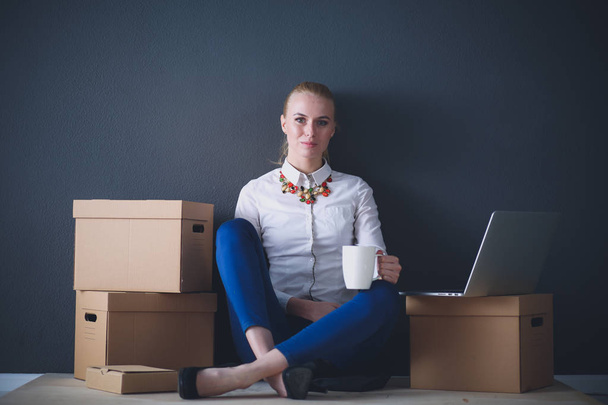 Woman sitting on the floor near a boxes with laptop . Businesswoman - Φωτογραφία, εικόνα