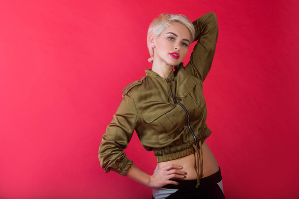 beautiful stylish young girl with short hairdo on red background with relaxed facial expression - Fotó, kép