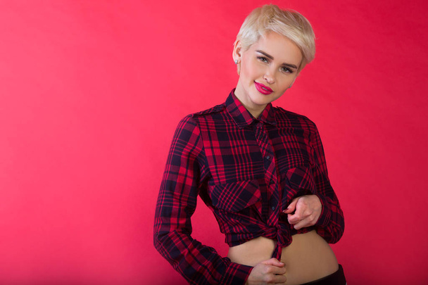 beautiful stylish young girl with short hairdo on red background with relaxed facial expression - Zdjęcie, obraz
