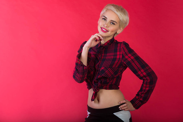 beautiful young girl with snow-white smile and healthy teeth with short hairdo to shirt on red background - Foto, immagini