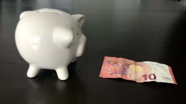 Kobieta, wprowadzenie banknotów Euro dziesięć do piggy bank - Materiał filmowy, wideo