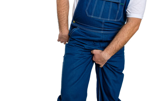 Man wearing denim dungarees scratching his crotch - Foto, afbeelding