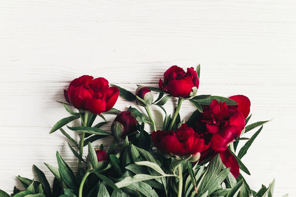tarjeta de felicitación de primavera con peonías rojas sobre fondo rústico de madera blanca
. - Foto, imagen