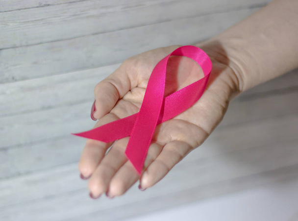 Woman hand giving satin pink ribbon, supporting symbol of breast cancer awareness campaign. - Foto, Imagem