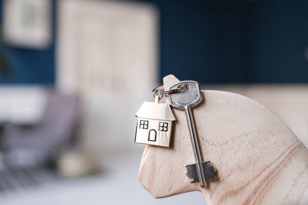 Ключ от дома и брелок в виде домов лежат на деревянных досках. Концепция недвижимости, ипотеки, переезда или аренды недвижимости
. - Фото, изображение