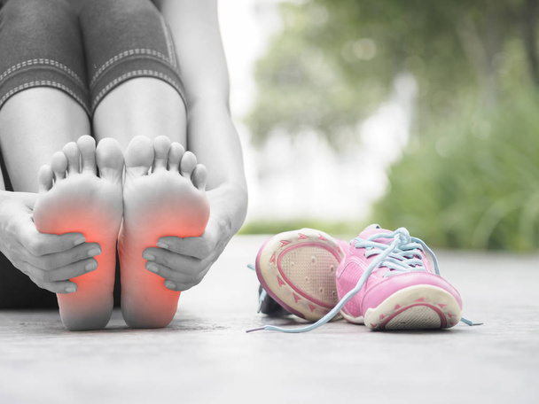 Closeup woman massaging her painful foot while exercising.    - 写真・画像