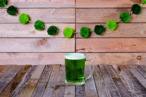 Taza de cerveza verde San Patricio jalá sobre fondo de madera
 - Foto, imagen