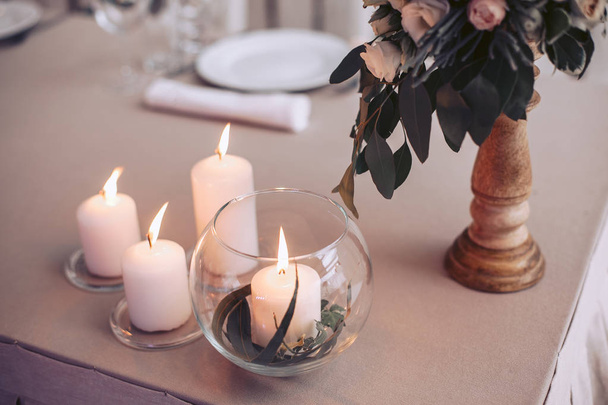 Wedding table with candles and a bouquet of flowers in soft colors - Fotó, kép