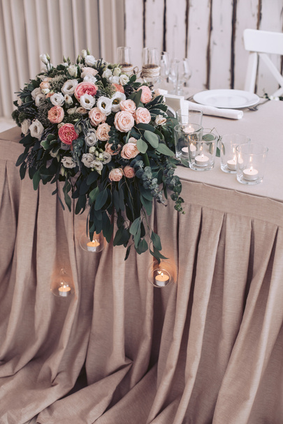 Um buquê de casamento de flores em uma mesa e velas ardentes em castiçais
 - Foto, Imagem