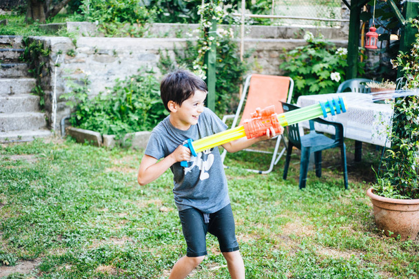 дети играют в саду с пистолетами и водяными винтовками на солнце
 - Фото, изображение