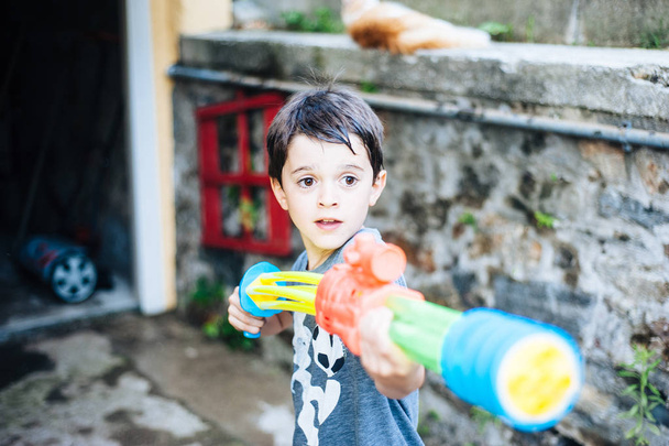 children play in the garden with guns and water rifles on a sunn - Photo, Image
