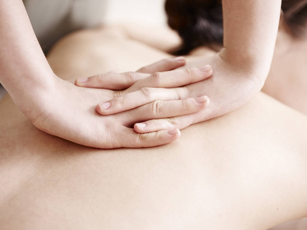 handen van de masseuse massage uitvoeren op jonge Aziatische vrouw - Foto, afbeelding