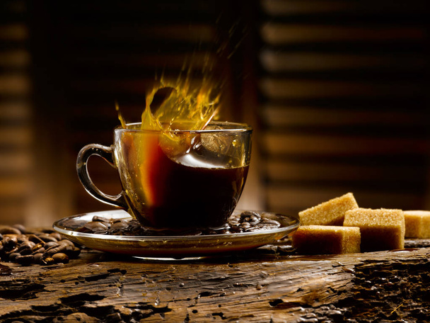 всплески кофе, деревенская обстановка с кофейными зернами и кубиками сахара
 - Фото, изображение