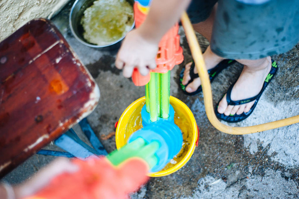 lapset leikkivät puutarhassa aseilla ja vesikivääreillä aurinkoisena kesäpäivänä, jolla on hauskaa
 - Valokuva, kuva