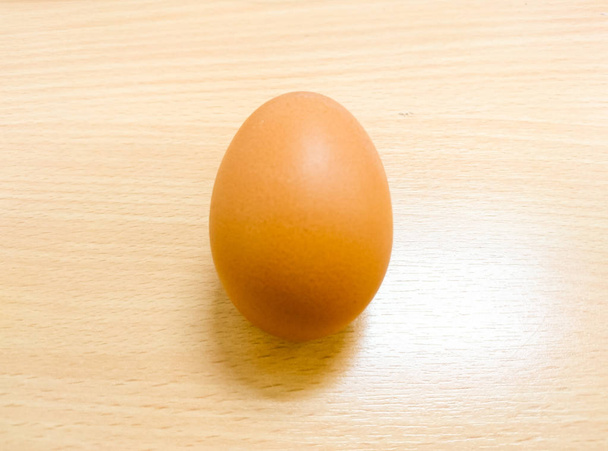 Ένα αυγό που βρίσκεται πάνω στο ξύλινο τραπέζι - Φωτογραφία, εικόνα