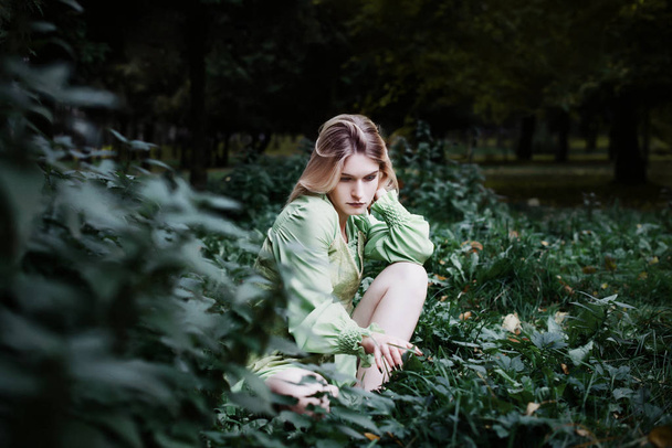 Mavka. Piękna kobieta w zielonej sukni jest chodzenie po lesie. - Zdjęcie, obraz