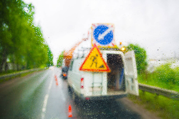 Δρόμο εργαζόμενοι του αυτοκινήτου μέσα από το παράθυρο με τη βροχή που πέφτει. - Φωτογραφία, εικόνα