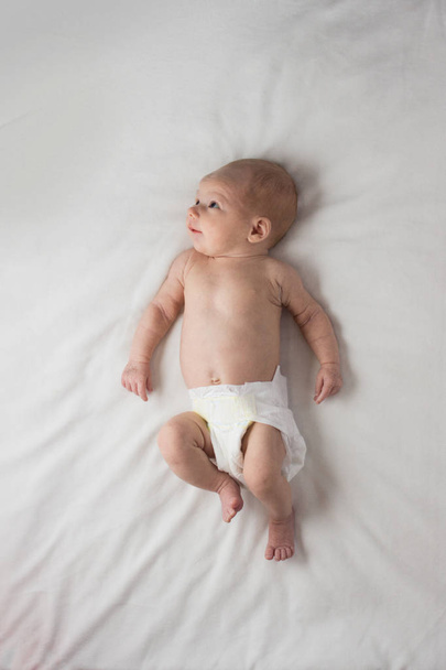 A Little Baby in a Diaper Lies on a white blanket. White backgro - Photo, Image
