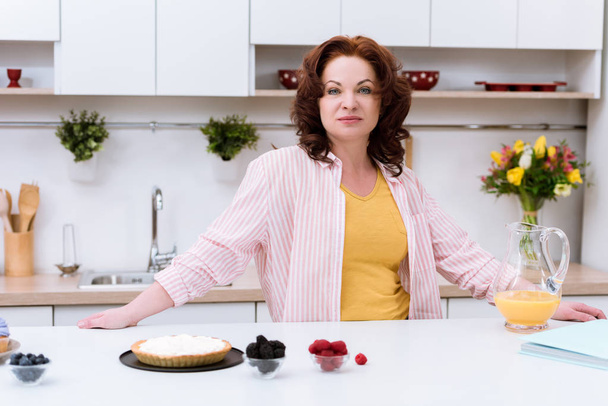 krásná zralá žena s dort a jahody v kuchyni - Fotografie, Obrázek
