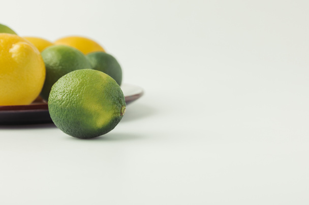 Green limes and lemons on plate on white background - Foto, Imagem