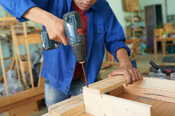 Carpintero profesional que conecta tablones de madera con tornillos
 - Foto, Imagen