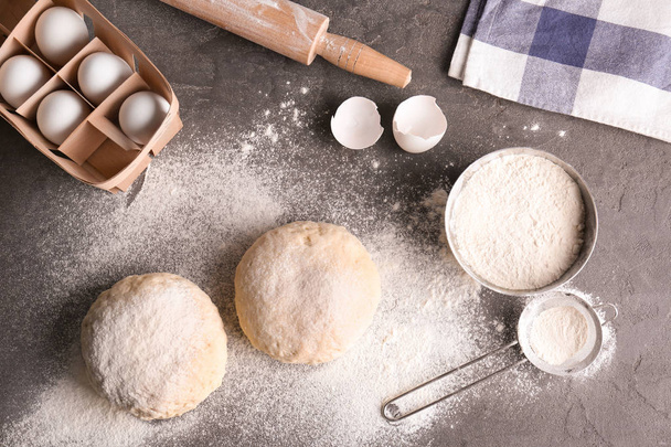 Raw dough with ingredients on kitchen table - 写真・画像