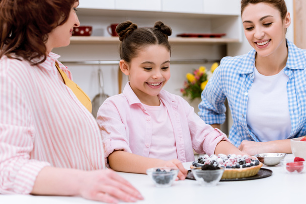 kolme sukupolvea naisia herkullinen torttu keittiössä
 - Valokuva, kuva