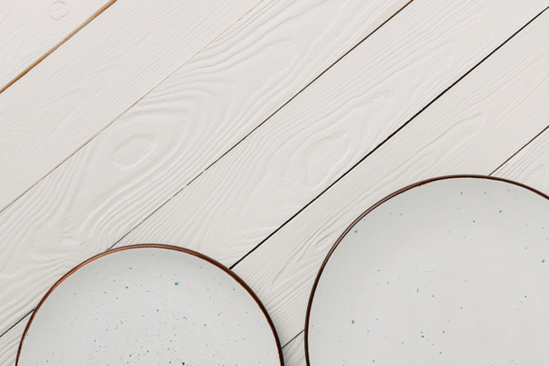 Placas esmaltadas vacías sobre fondo blanco de madera
 - Foto, Imagen