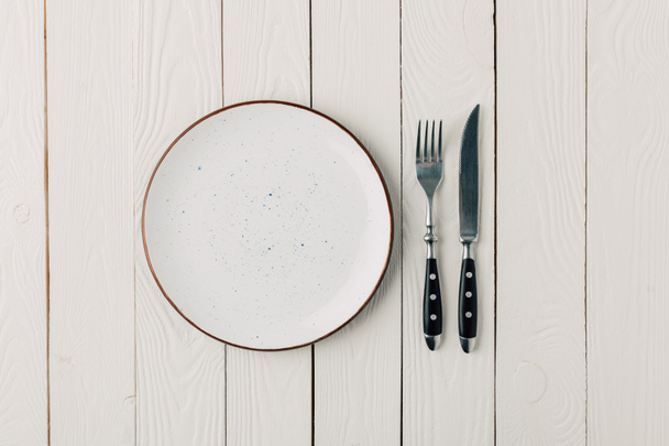 leerer Teller und Besteck auf weißem Holzgrund - Foto, Bild
