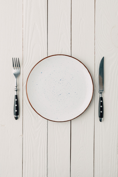 Top view of plate and cutlery on white wooden background - Photo, Image