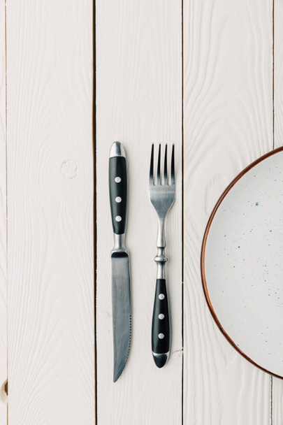 top view of empty plate and silverware on white wooden background - Valokuva, kuva