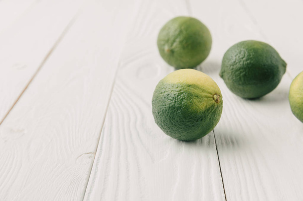 Raw green limes on white wooden background - Photo, image
